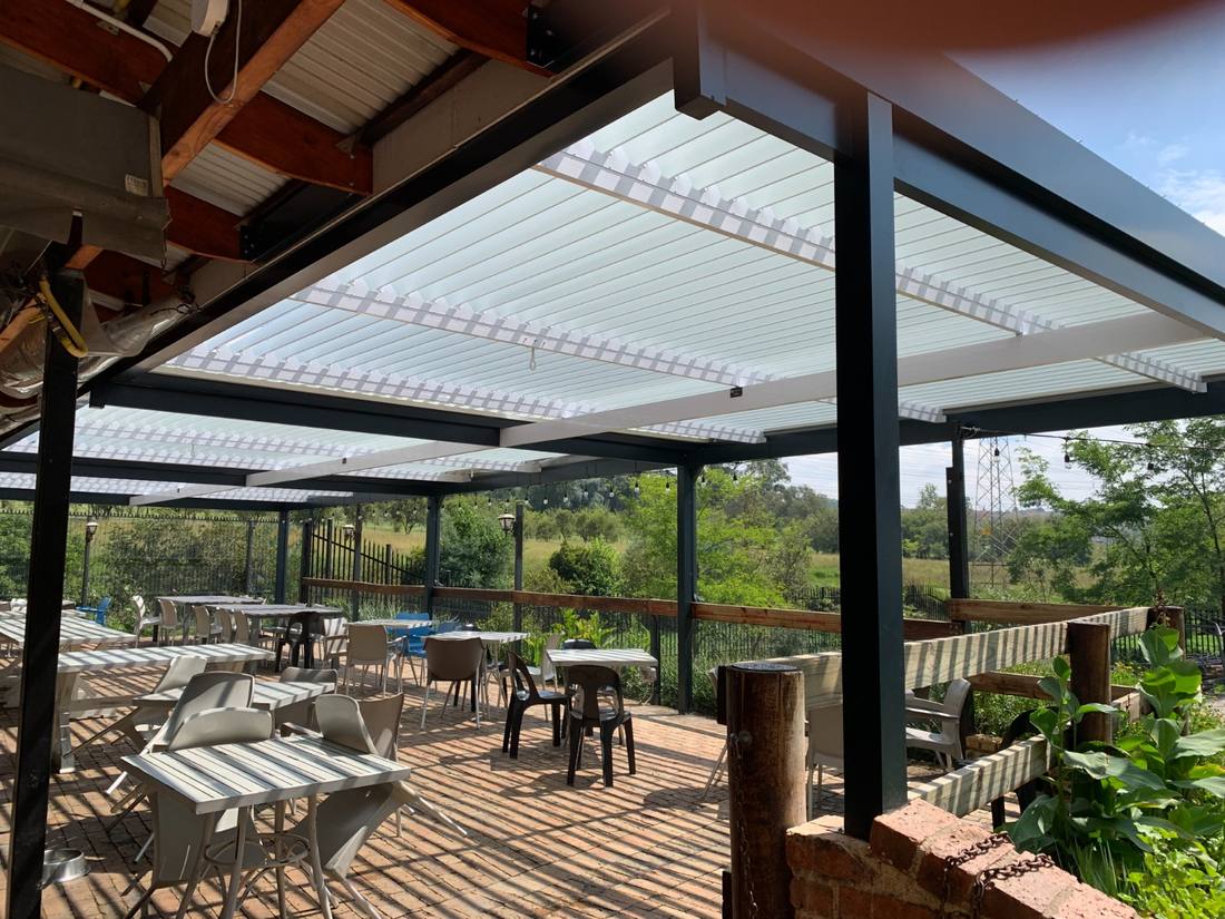 White-bladed louvre roof with festoon lighting over a restaurant dining deck