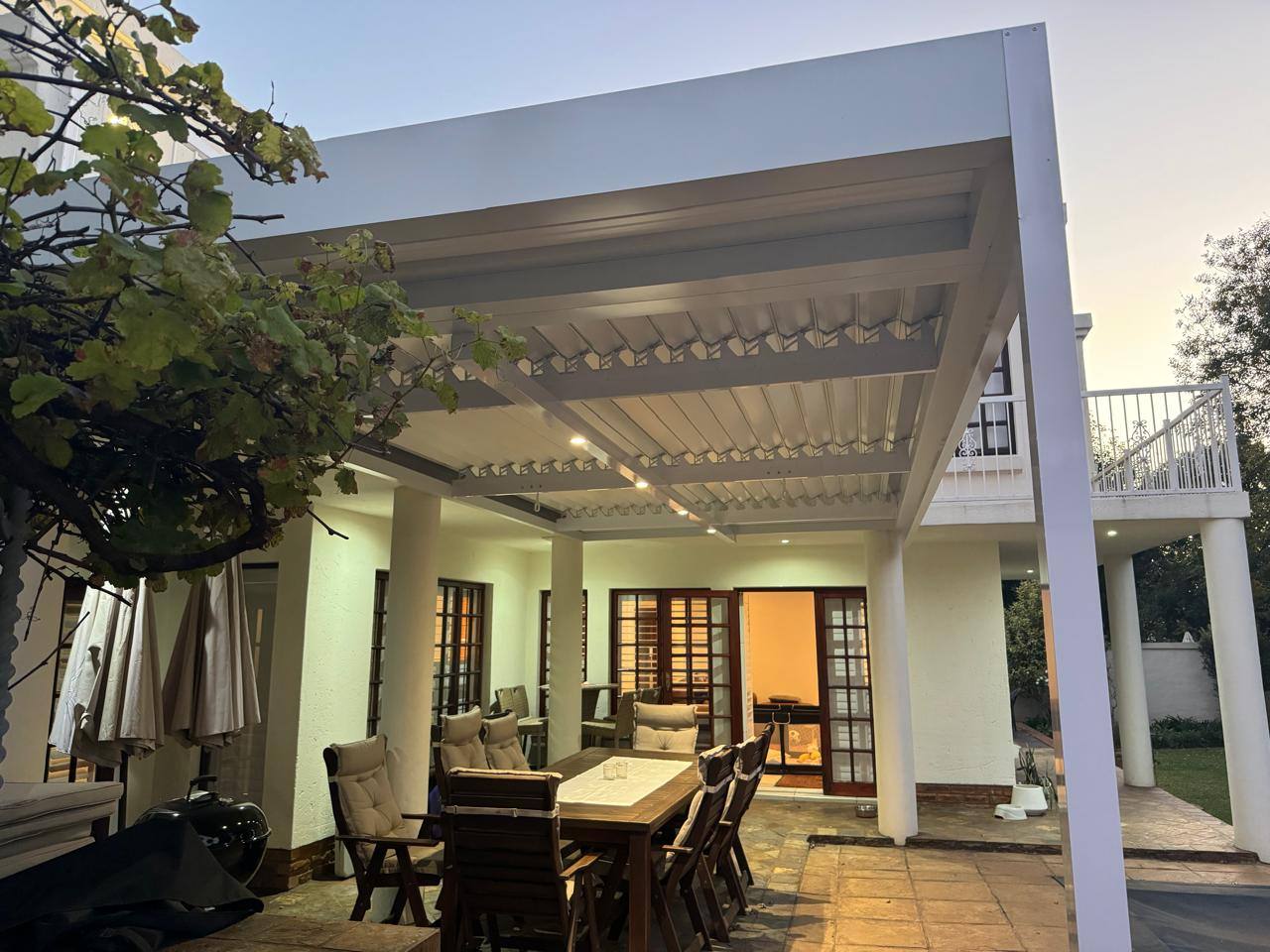 White louvre with downlights lit at dusk over a dining patio in Benoni