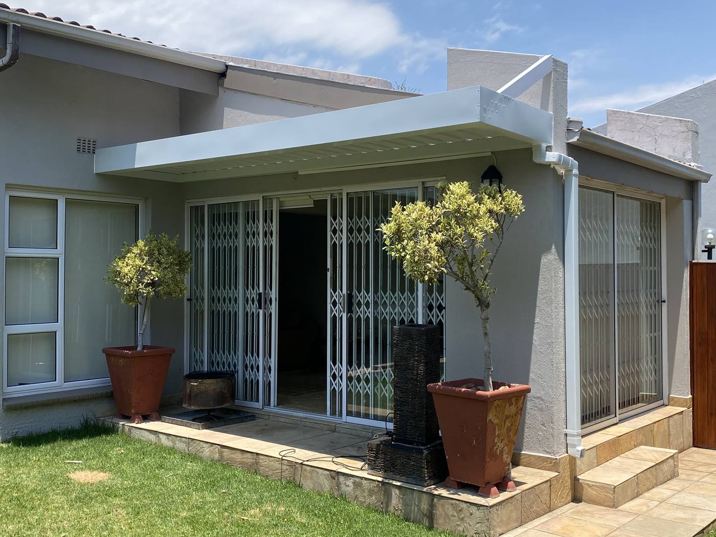 White fixed IBR awning spanning two sets of sliding doors